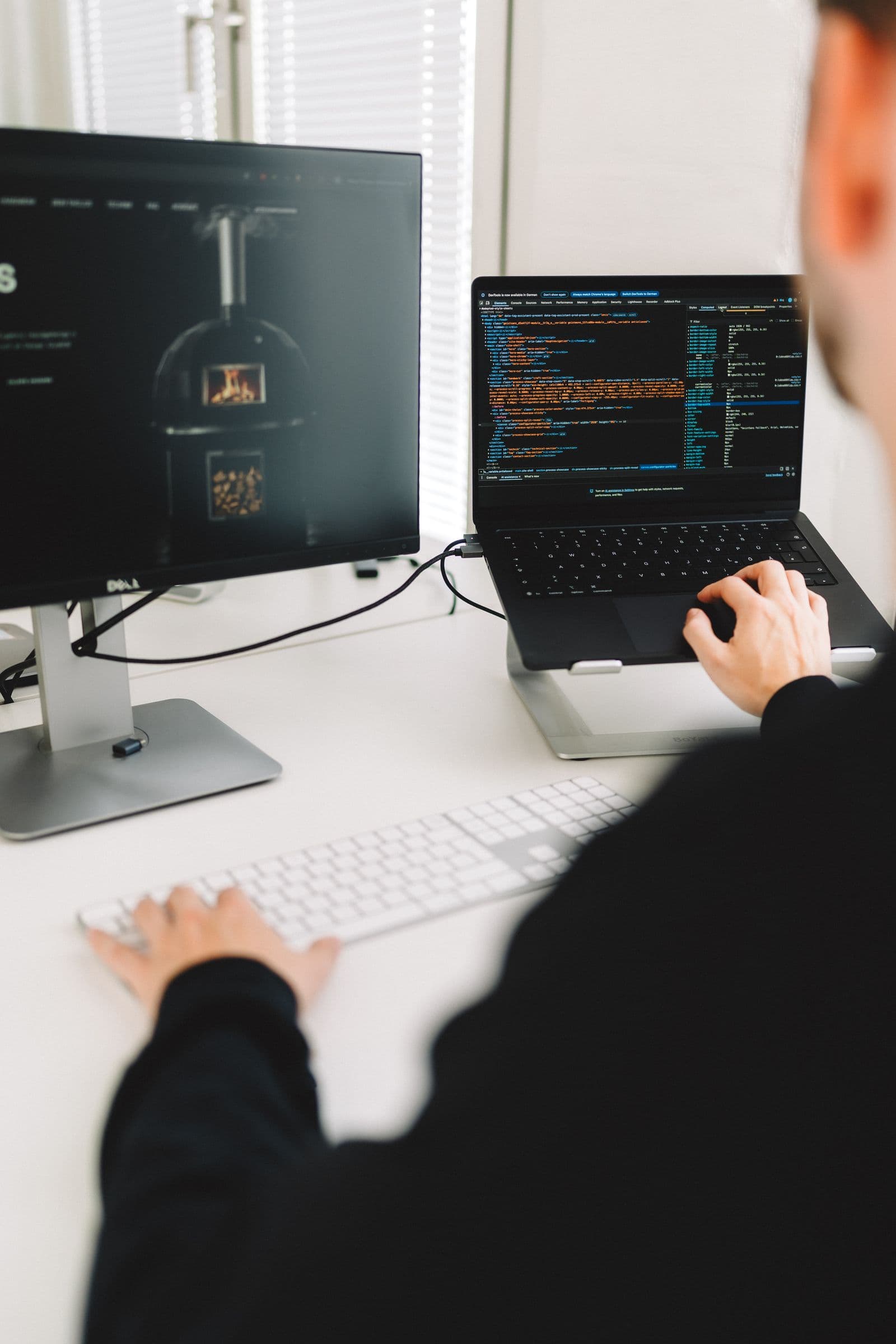 Arbeiten an Monitor und Laptop, auf dem Bildschirm die Tholos-Website