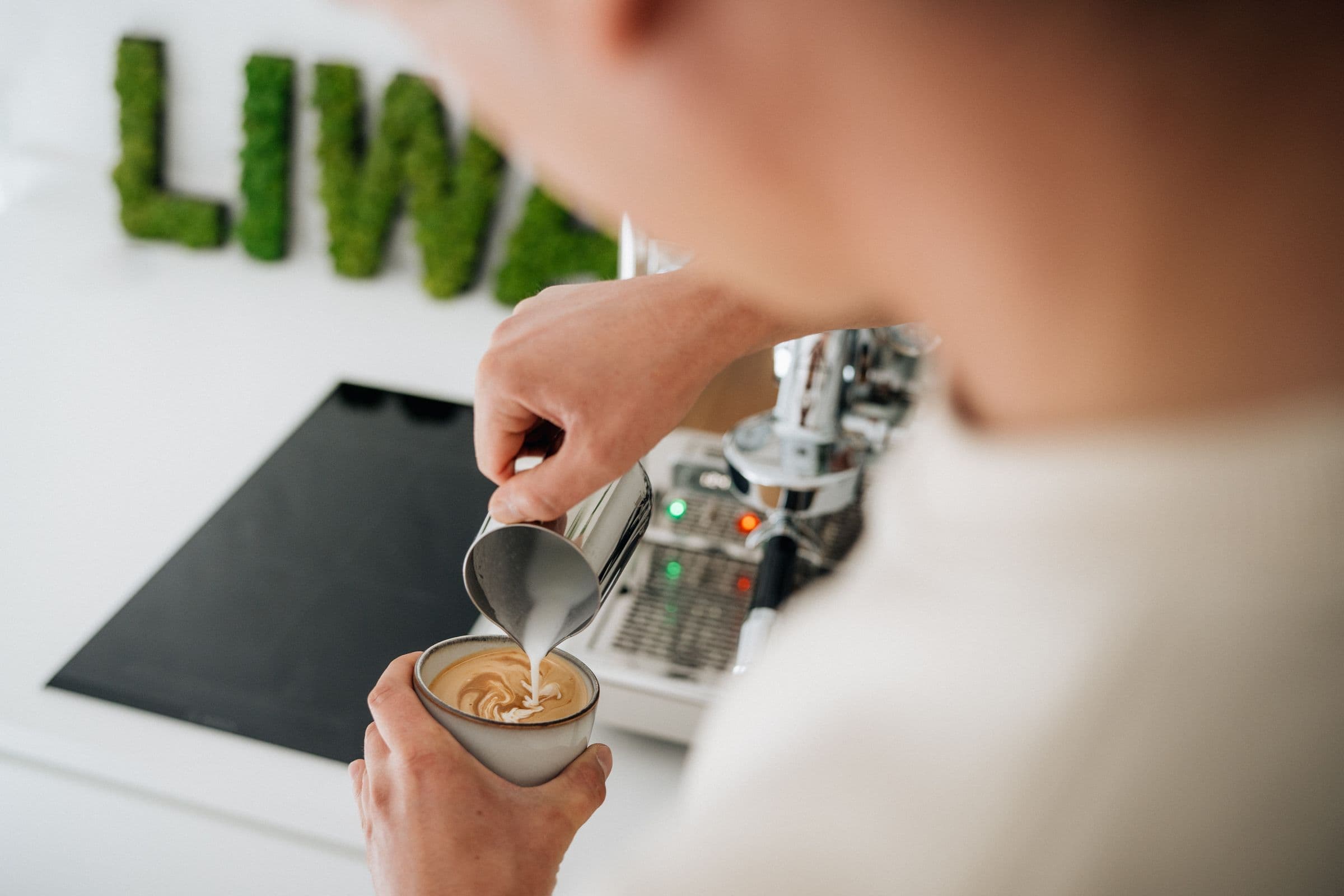 Latte Art wird vor dem LIWA-Schriftzug aus Moos gegossen