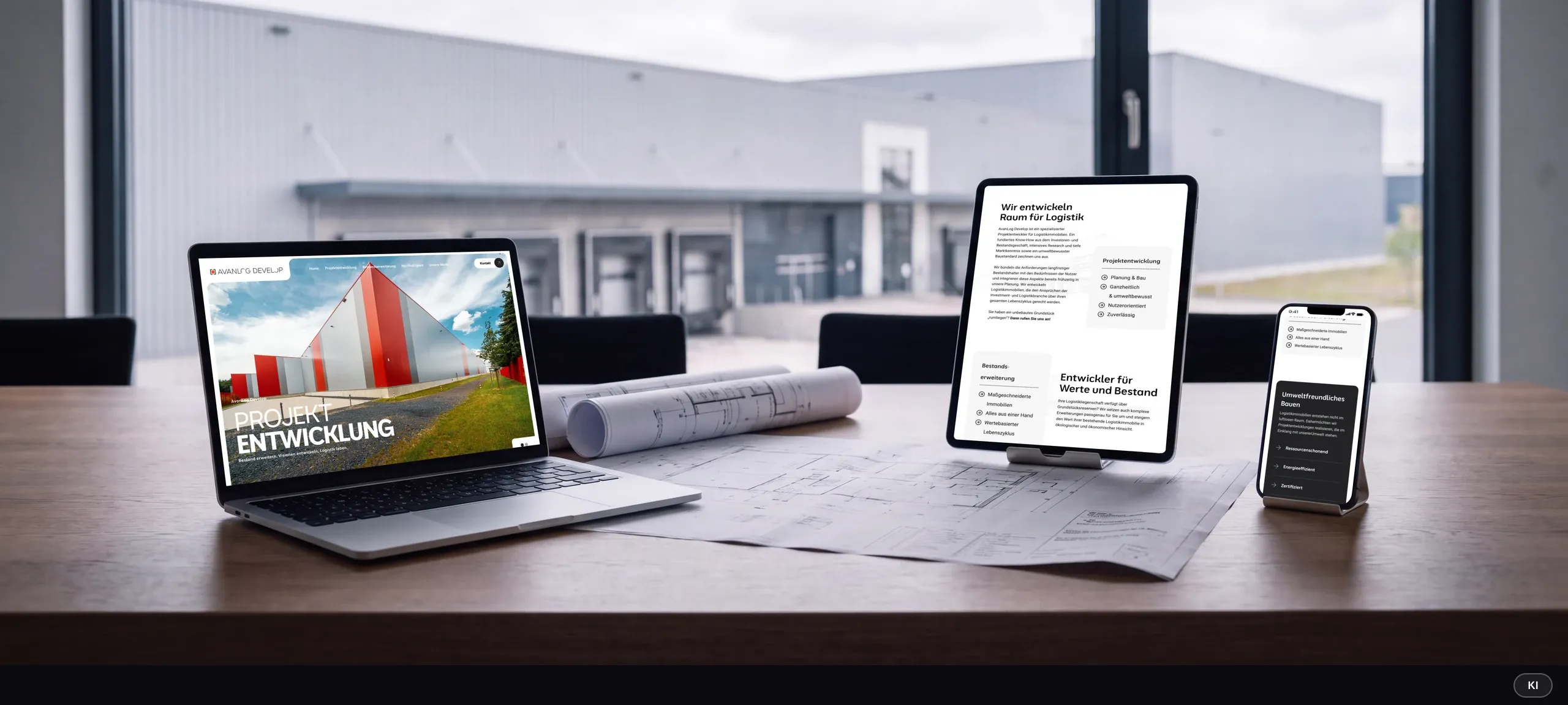 KI-generiertes Bild: Laptop, Tablet und Smartphone zeigen Startseite, Projektentwicklung und Umweltfreundliches Bauen der AvanLog-Website auf einem Besprechungstisch vor Logistikhallen