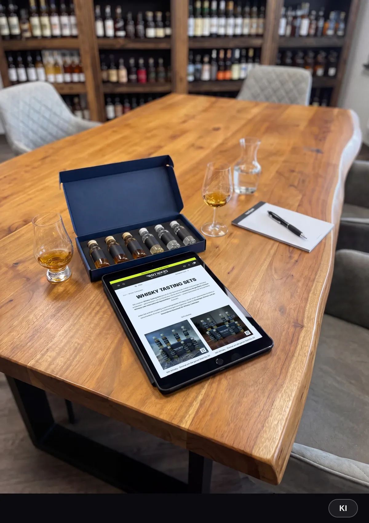 KI-generiertes Bild: Tablet mit der Übersicht der Whisky-Tasting-Sets auf einem Holztisch neben einem geöffneten Tasting-Set mit Sample-Fläschchen, Gläsern und Notizblock