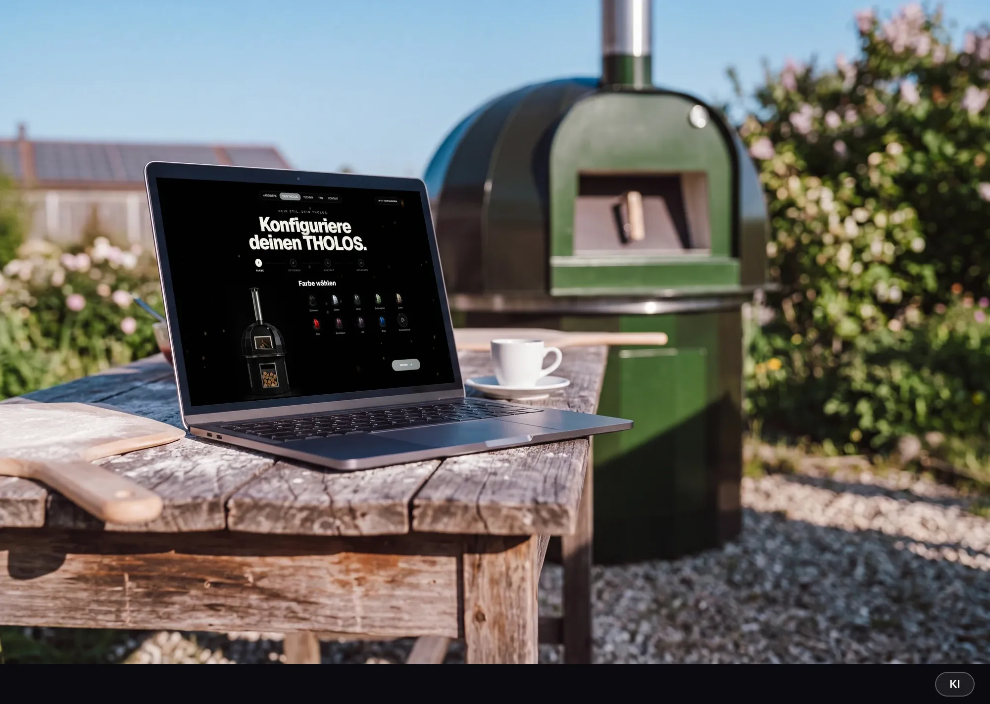KI-generiertes Bild: Laptop auf einem verwitterten Gartentisch zeigt den THOLOS-Konfigurator, dahinter der grüne Outdoor-Ofen im sonnigen Garten